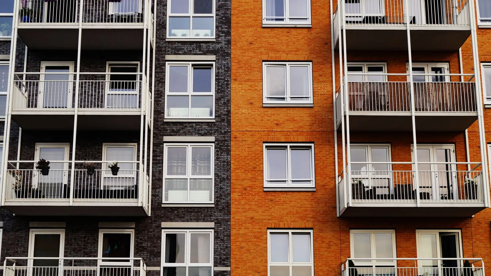 The facade of a modern apartment building with rows of balconies