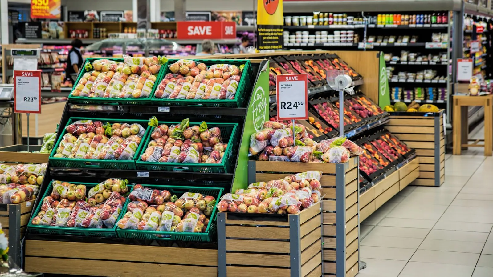A grocery store produce aisle with fresh fruit and price signs